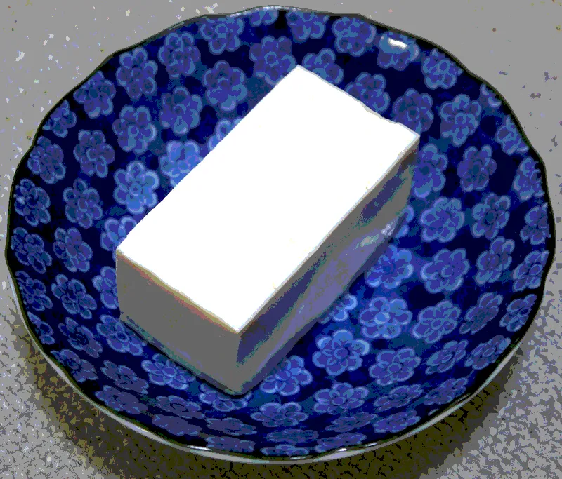 close up on a block of tofu on a round blue plate